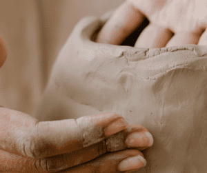 close-up of fingers hand-sculpting a clay pot