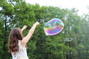 girl playing with giant soap bubble