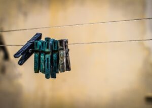 on a laundry line made of old string hang a cluster of battered colorful clothespins in violet, turquoise, aqua and greying brown: after enlightenment, we still have to integrate spiritual experience into everyday life, including doing the laundry